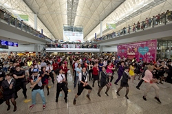 Dancers' enthusiastic performance in the Meeters and Greeters Hall entertains bystanders and passengers.